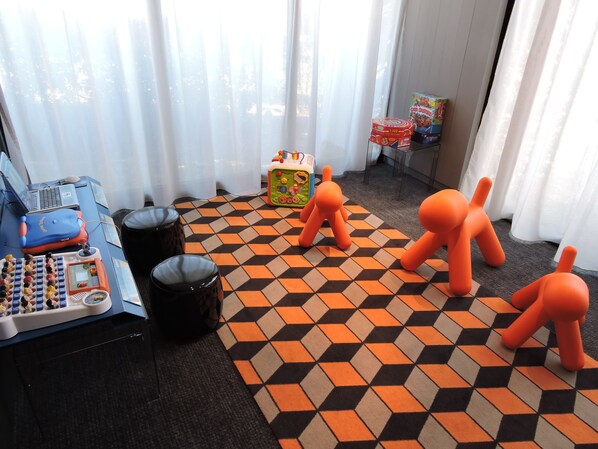 A room with a checkered floor, a desk with a computer, a toy, and a window with curtains.