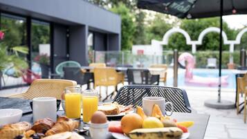 An outdoor dining area with a table set for breakfast, including croissants, eggs, and fruit.