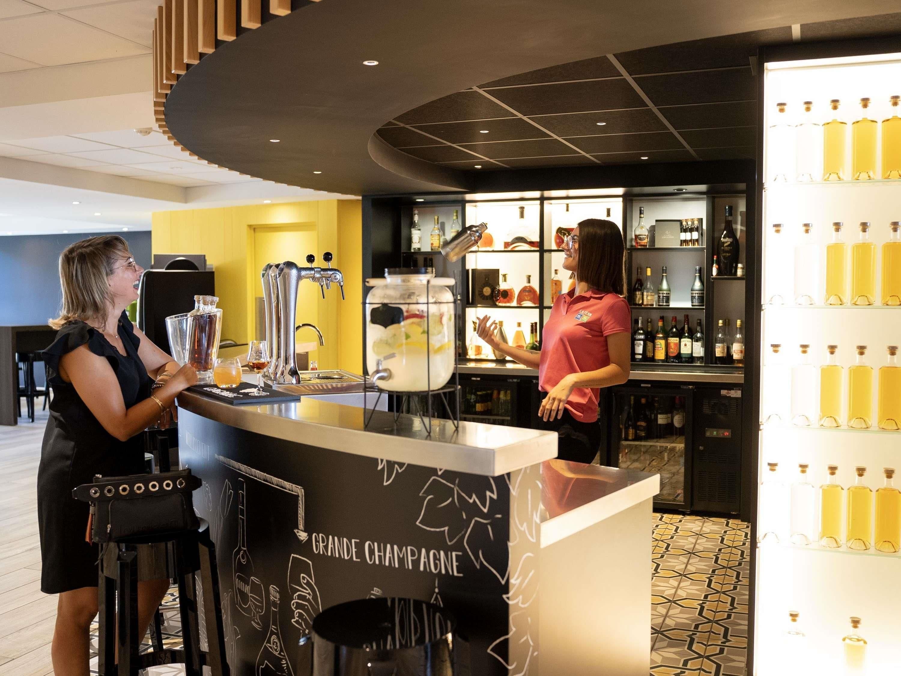 A bar area with a counter, a large tap, and a display of bottles.