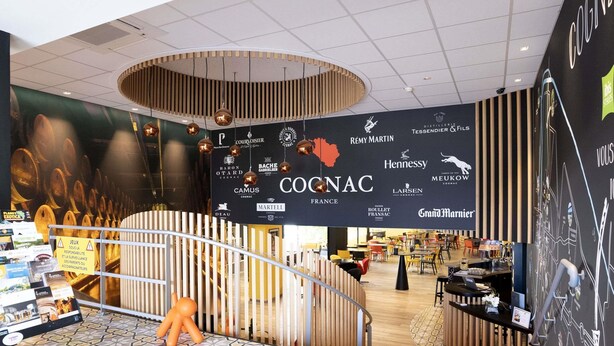 Ein modernes Interieur mit einem großen Schild für COCONAC, einer Treppe und einer Sitzgelegenheit mit orangefarbenen Stühlen.