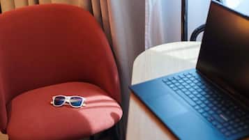 Uma cadeira vermelha com óculos de sol e um laptop sobre uma mesa.