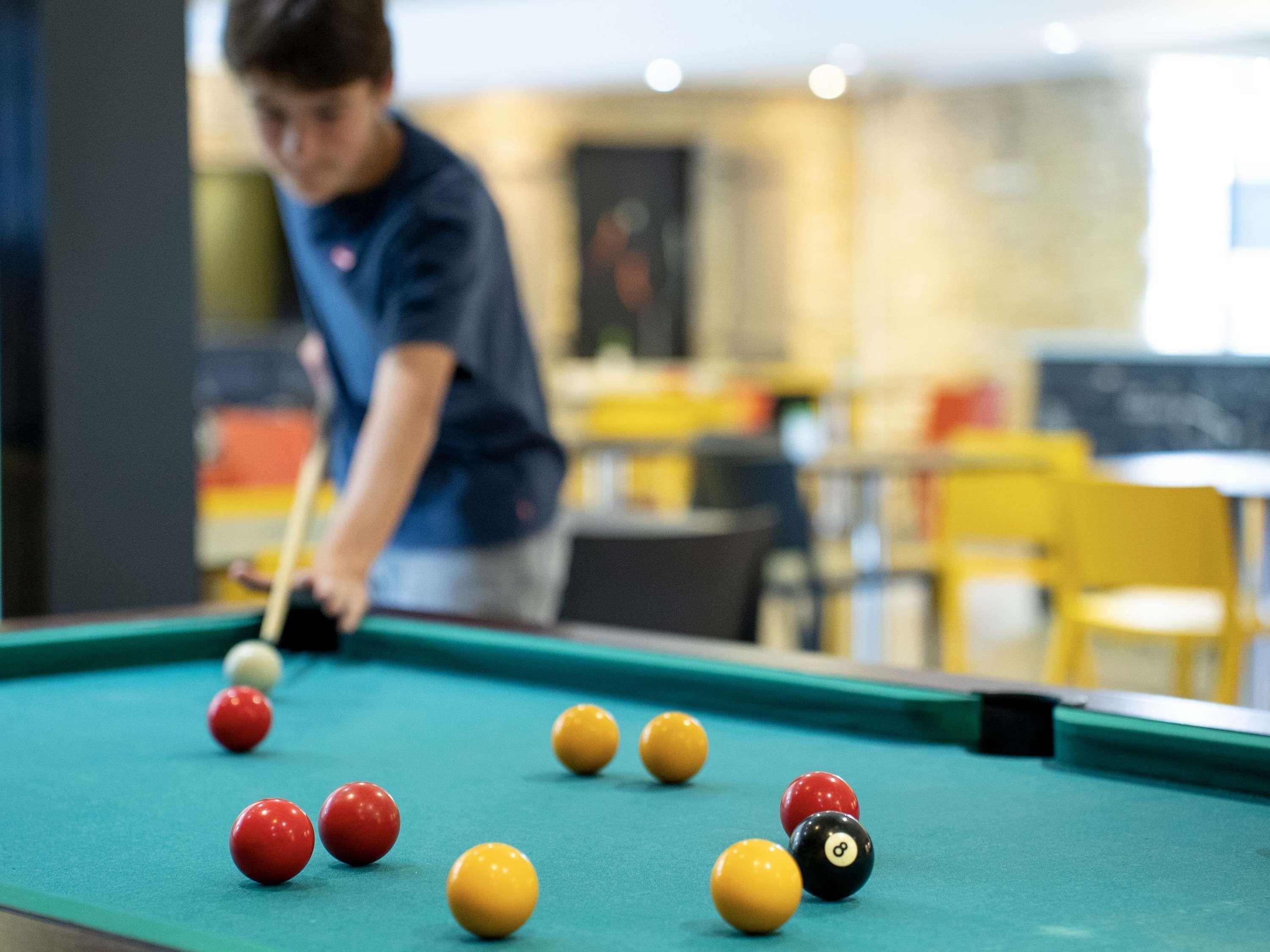 A pool table with balls and a person playing.