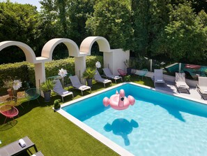 A swimming pool with lounge chairs, a flamingo float, and a turtle float.