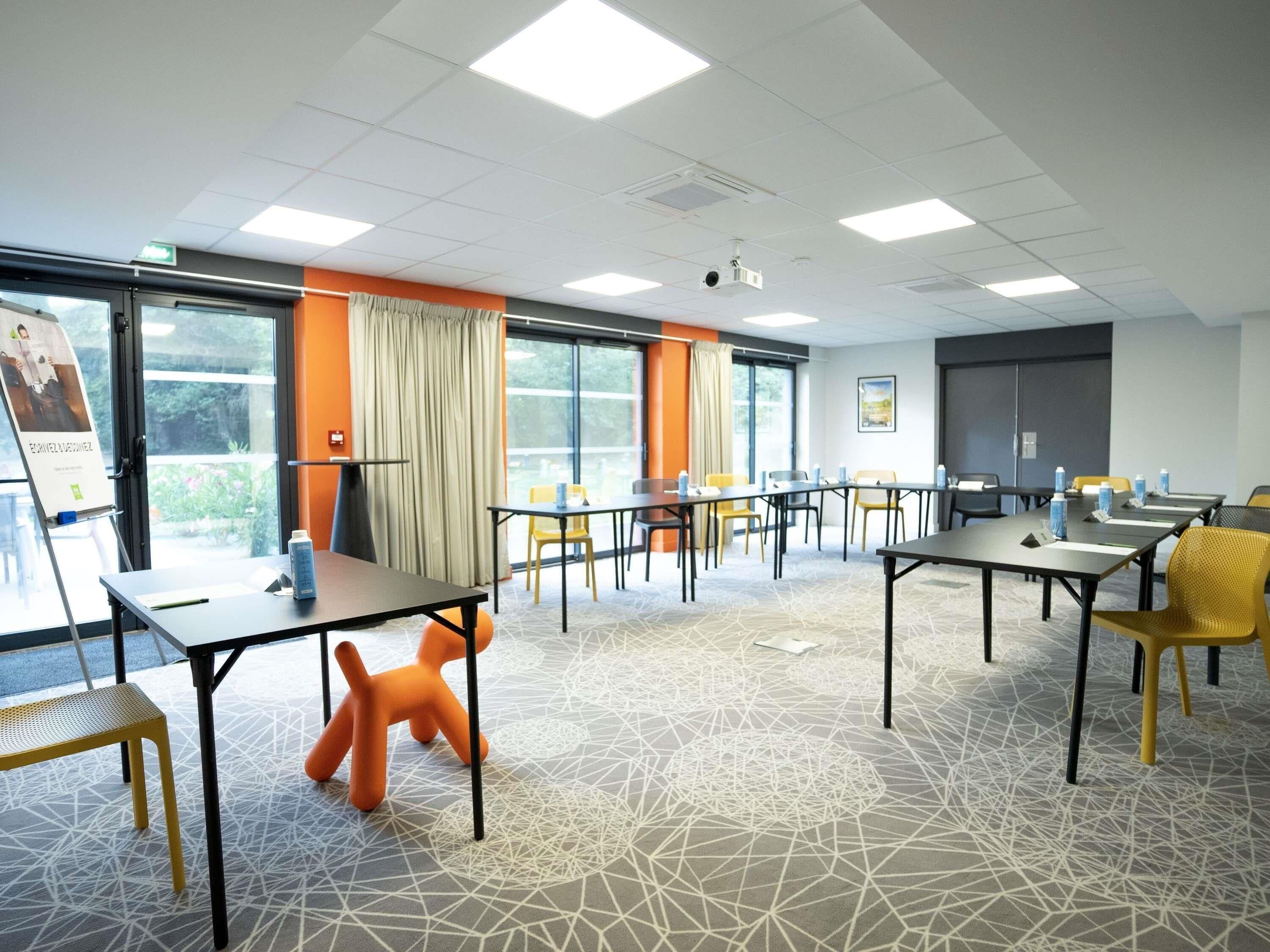 A conference room with tables, chairs, a projector, and a large window.