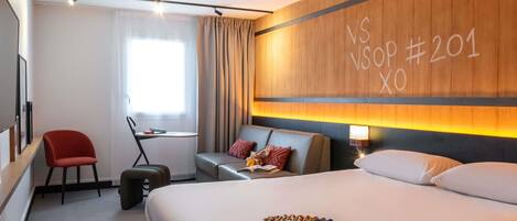 Ein Hotelzimmer mit Bett, Schreibtisch, Stuhl, Koffer und einer Wand mit einem Schild.