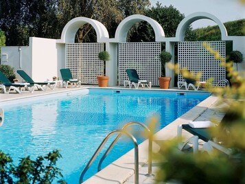 Una piscina al aire libre de temporada, tumbonas