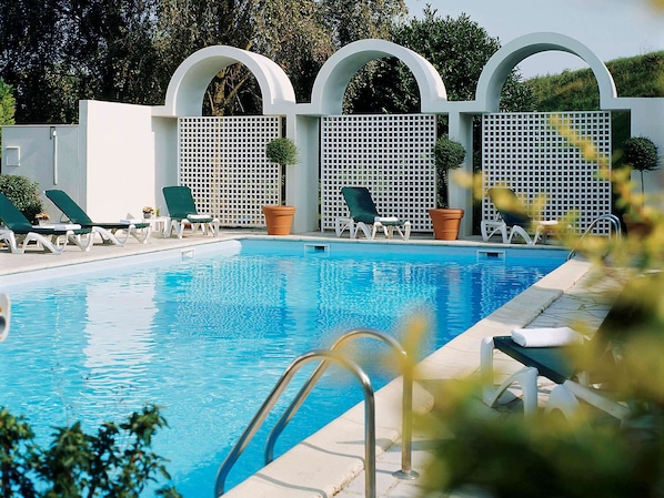 Una piscina al aire libre de temporada, tumbonas