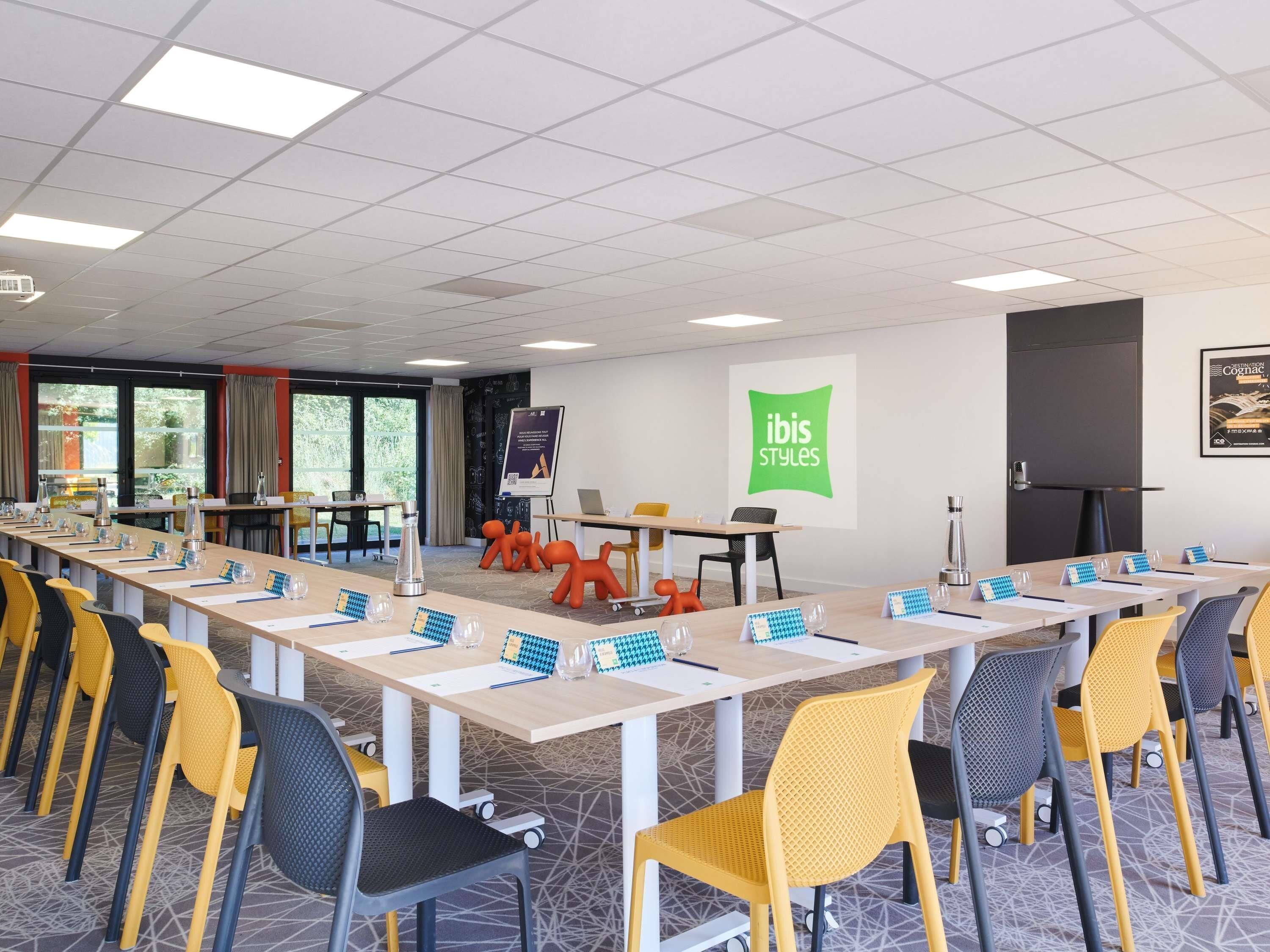 A conference room with a long table, chairs, and a presentation screen.