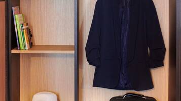A wooden wardrobe with a hanging coat, a hat, and a suitcase.