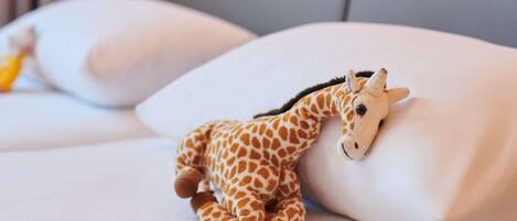 A bed with white pillows and a small stuffed giraffe toy on one pillow.