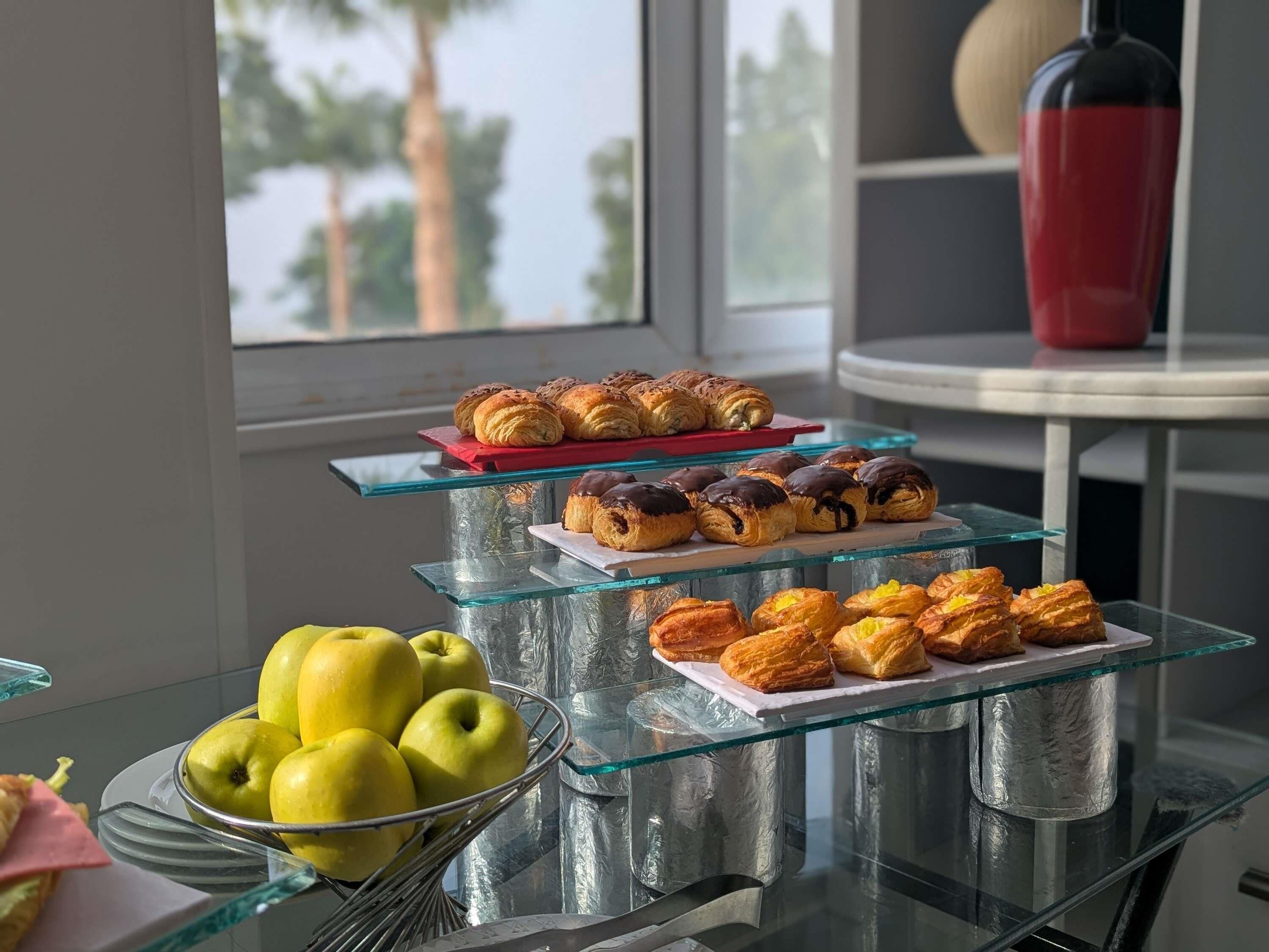 Una vitrina de vidrio con pasteles y un bol de manzanas.