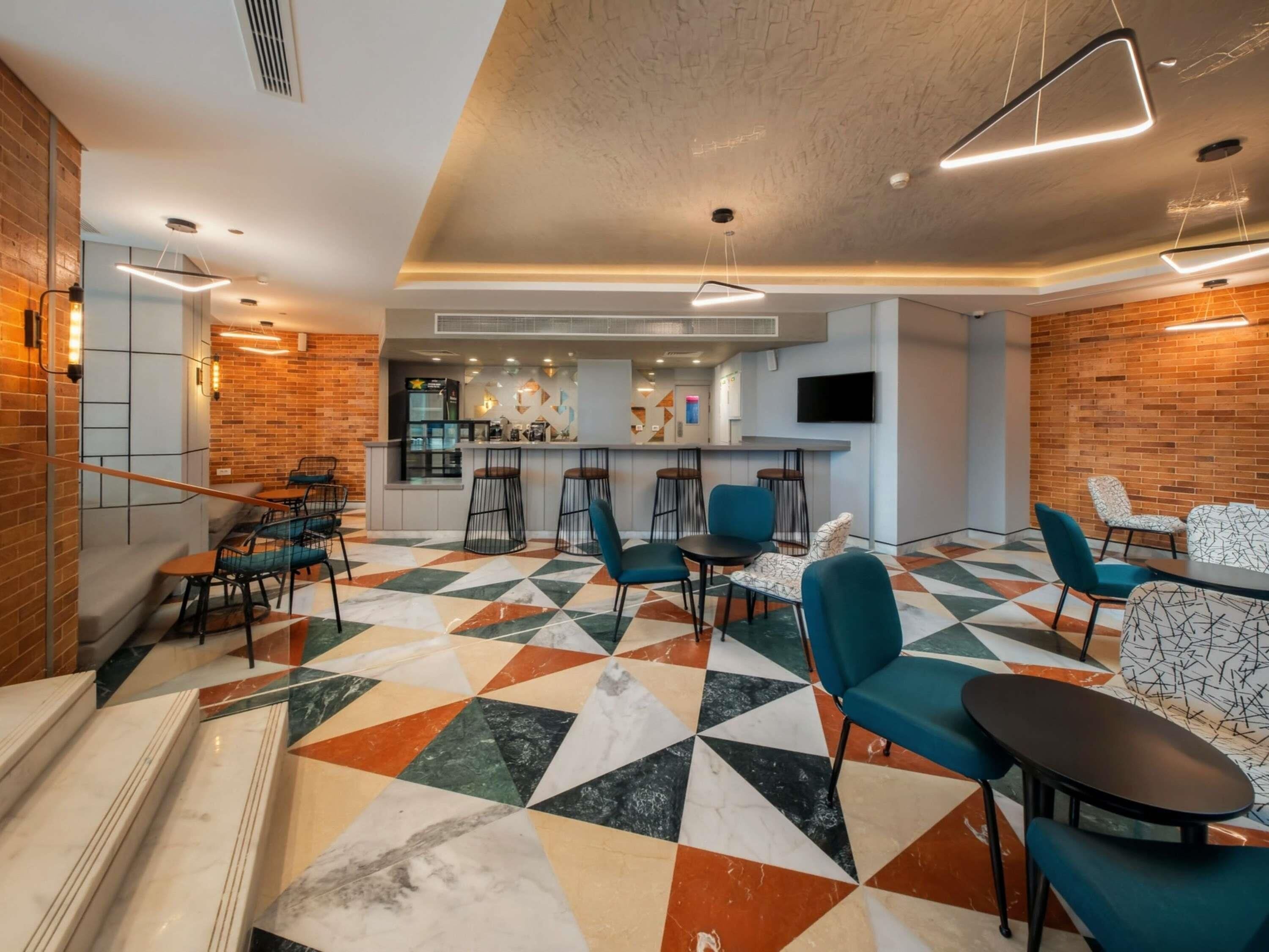 A modern lounge area with a geometric patterned floor, a bar area, and seating arrangements.