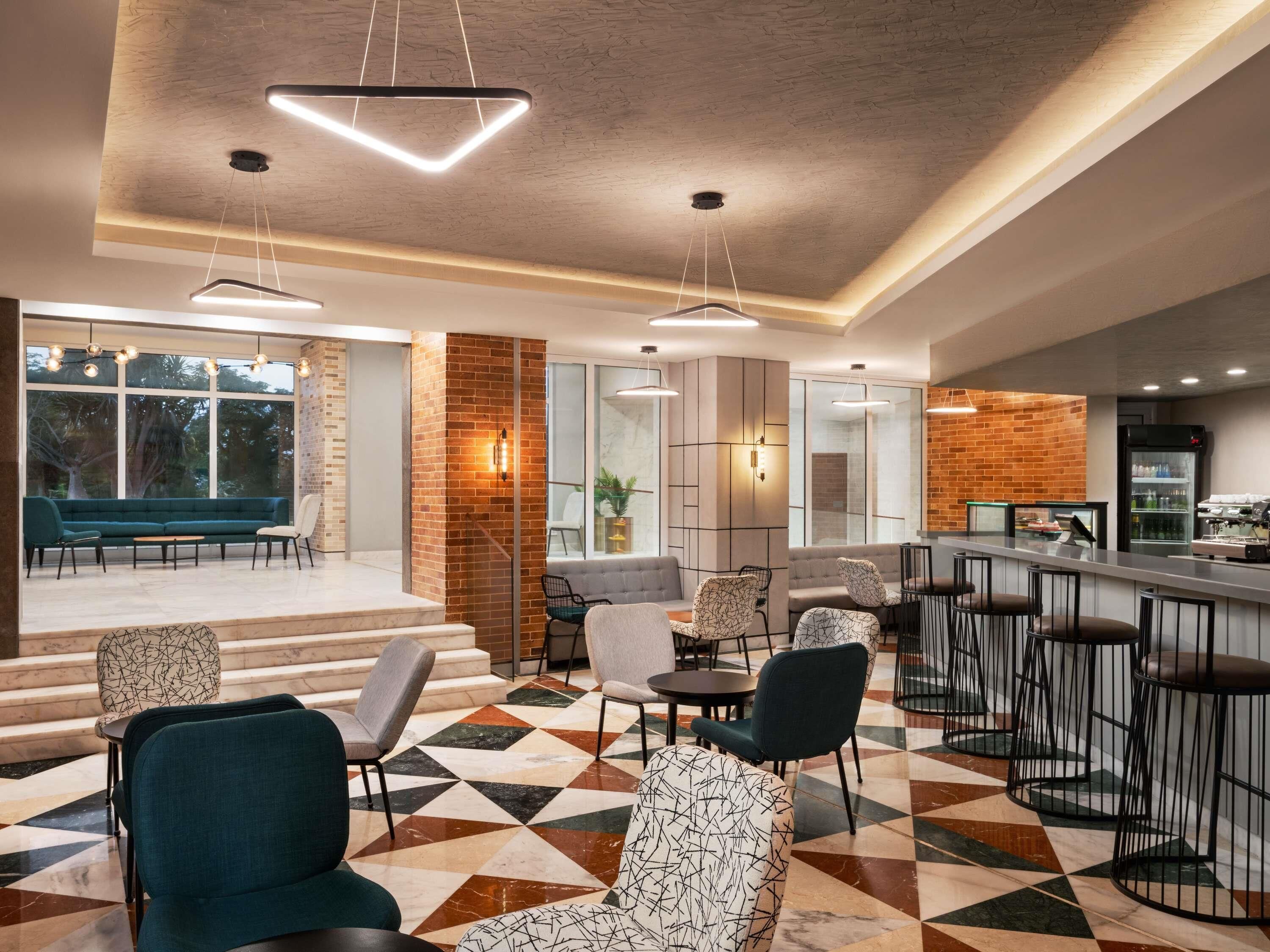 A modern lounge area with a mix of seating options, a patterned floor, and a bar area with stools.