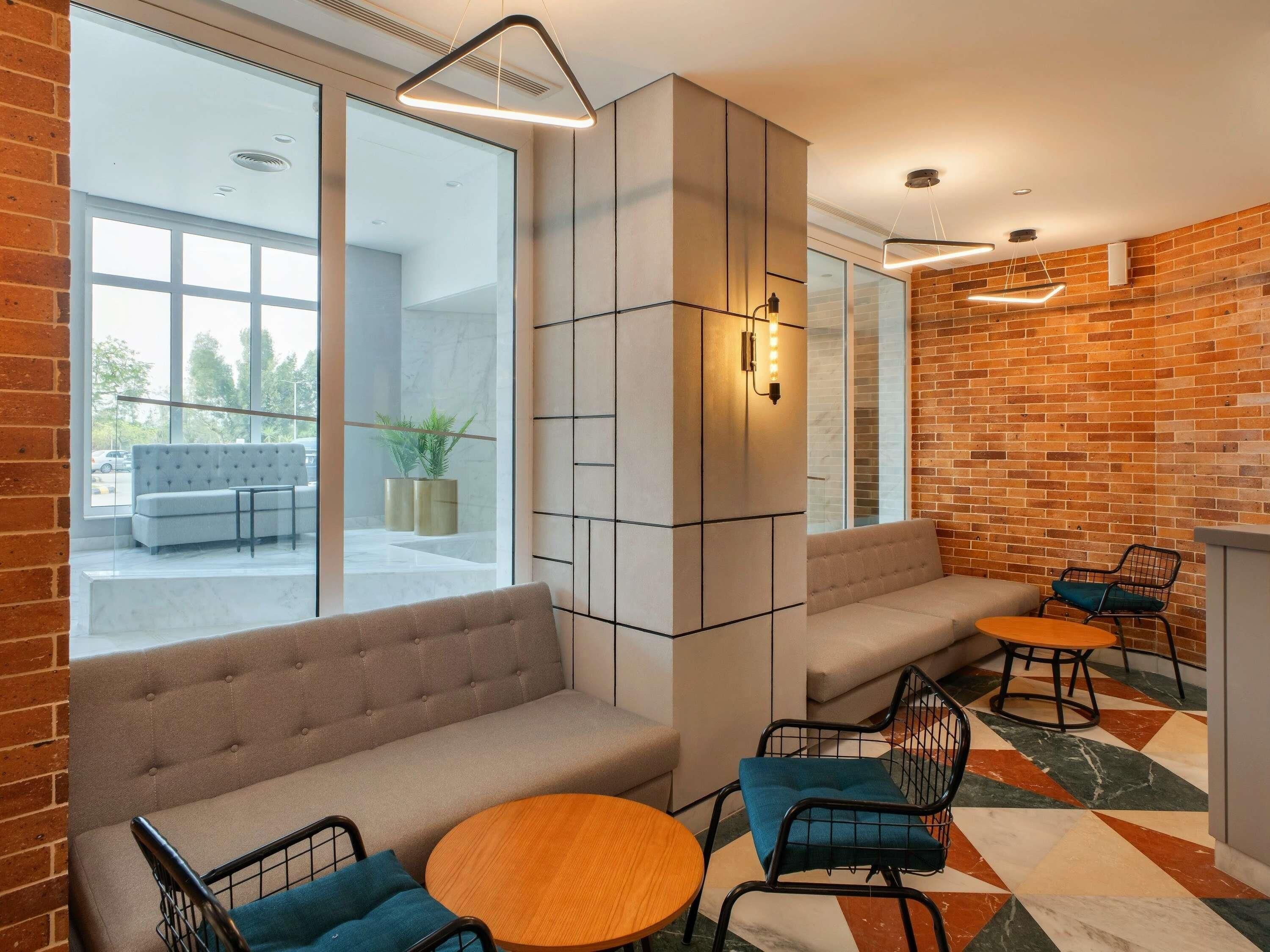 Un área de estar moderna con asientos, una mesa de centro y una pared de ladrillo.