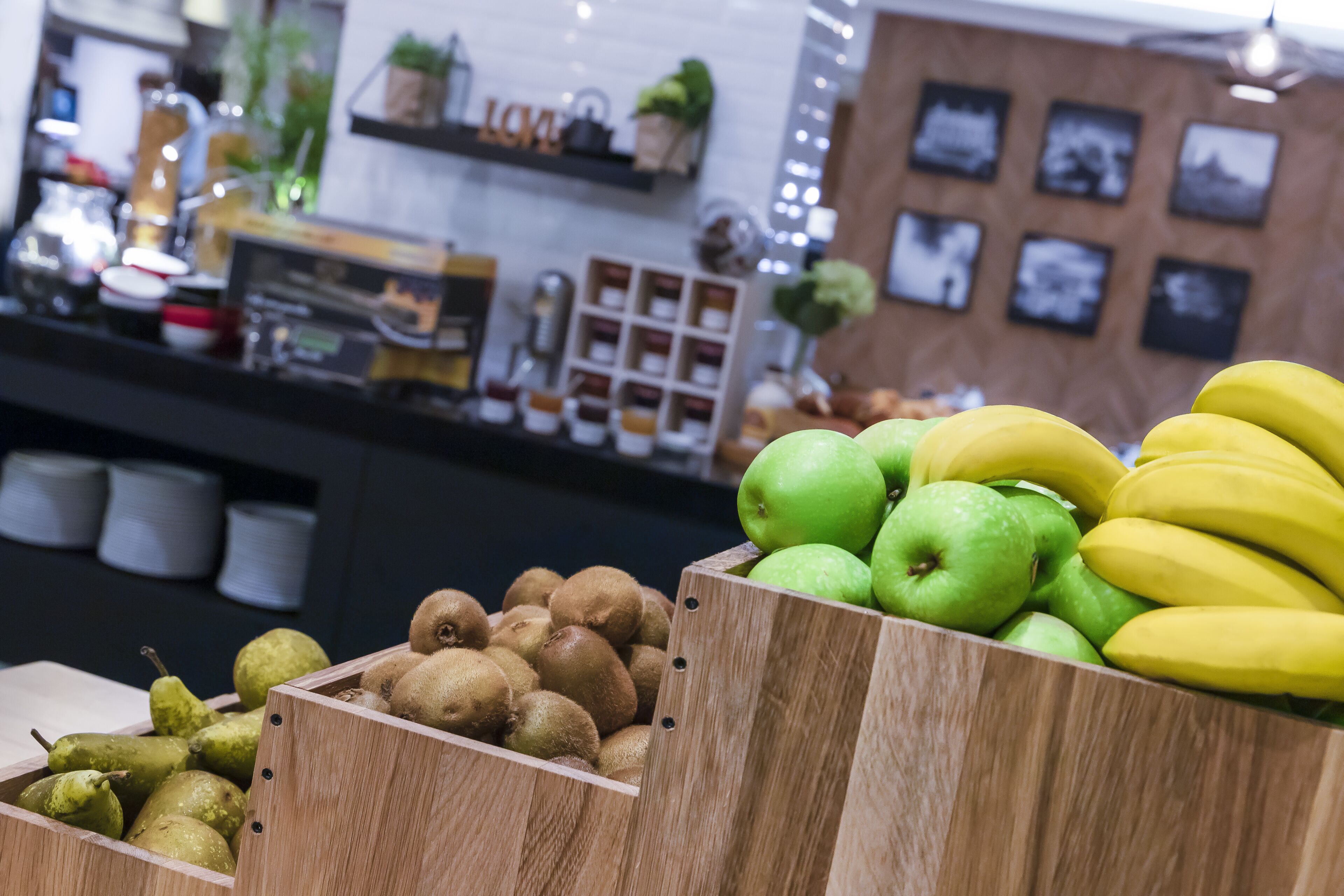 A wooden fruit display with kiwis, pears, and bananas.
