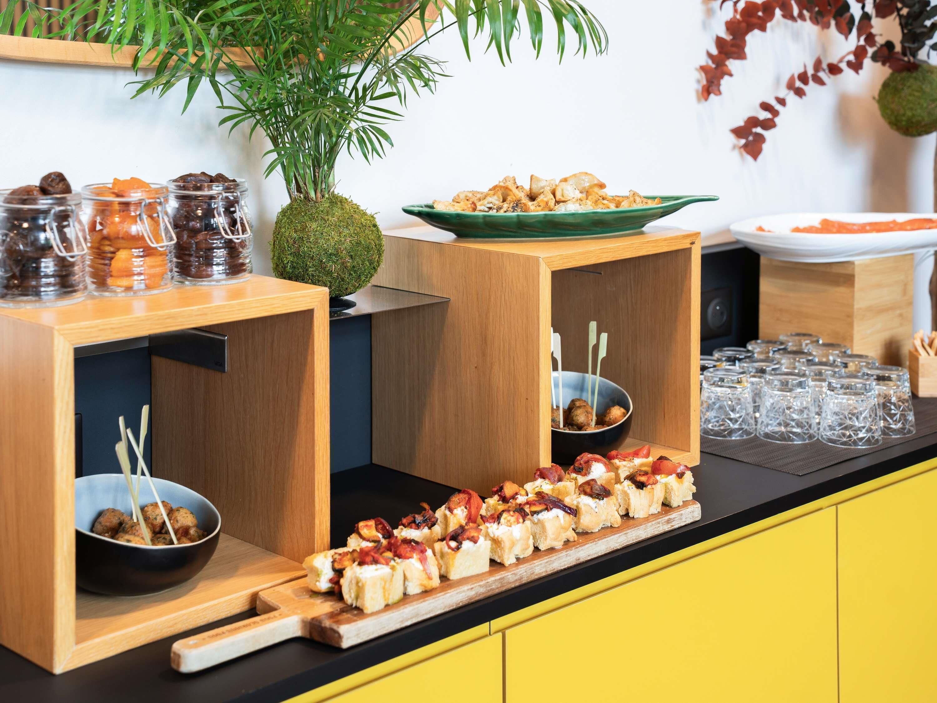 Ein reichhaltiges Buffet mit verschiedenen Speisen, darunter eine Schüssel Hackbällchen, eine Platte mit Vorspeisen und Gläsern eingelegter Gurken.