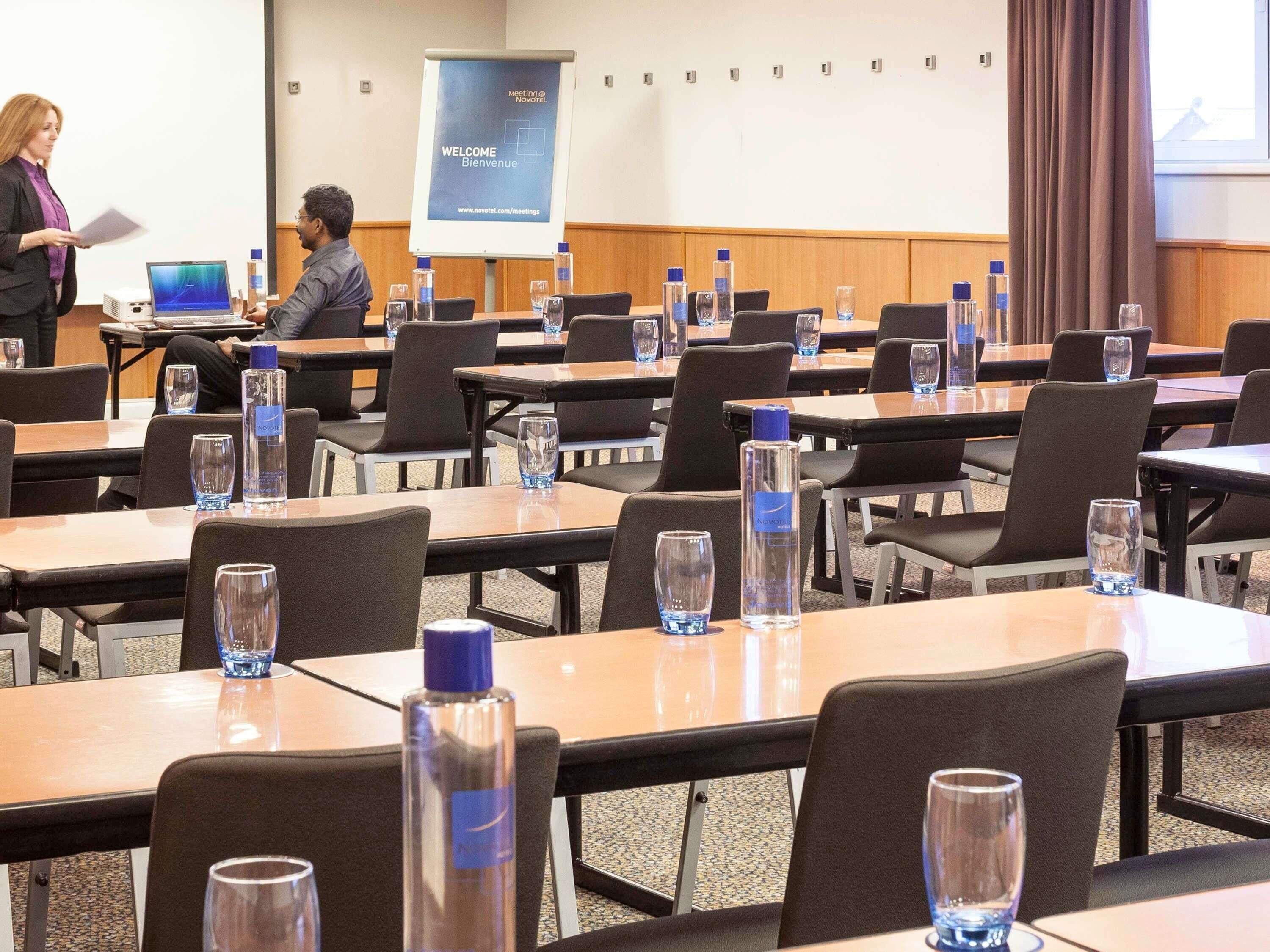 A conference room with tables, chairs, and a presentation screen.