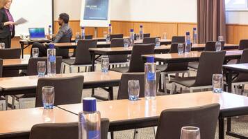 A conference room with tables, chairs, and a presentation screen.