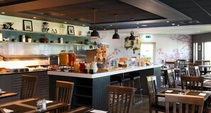 A restaurant with a central bar area, multiple seating options, and a decorative wall with floral patterns. - Novotel Milton Keynes (Milton Keynes)