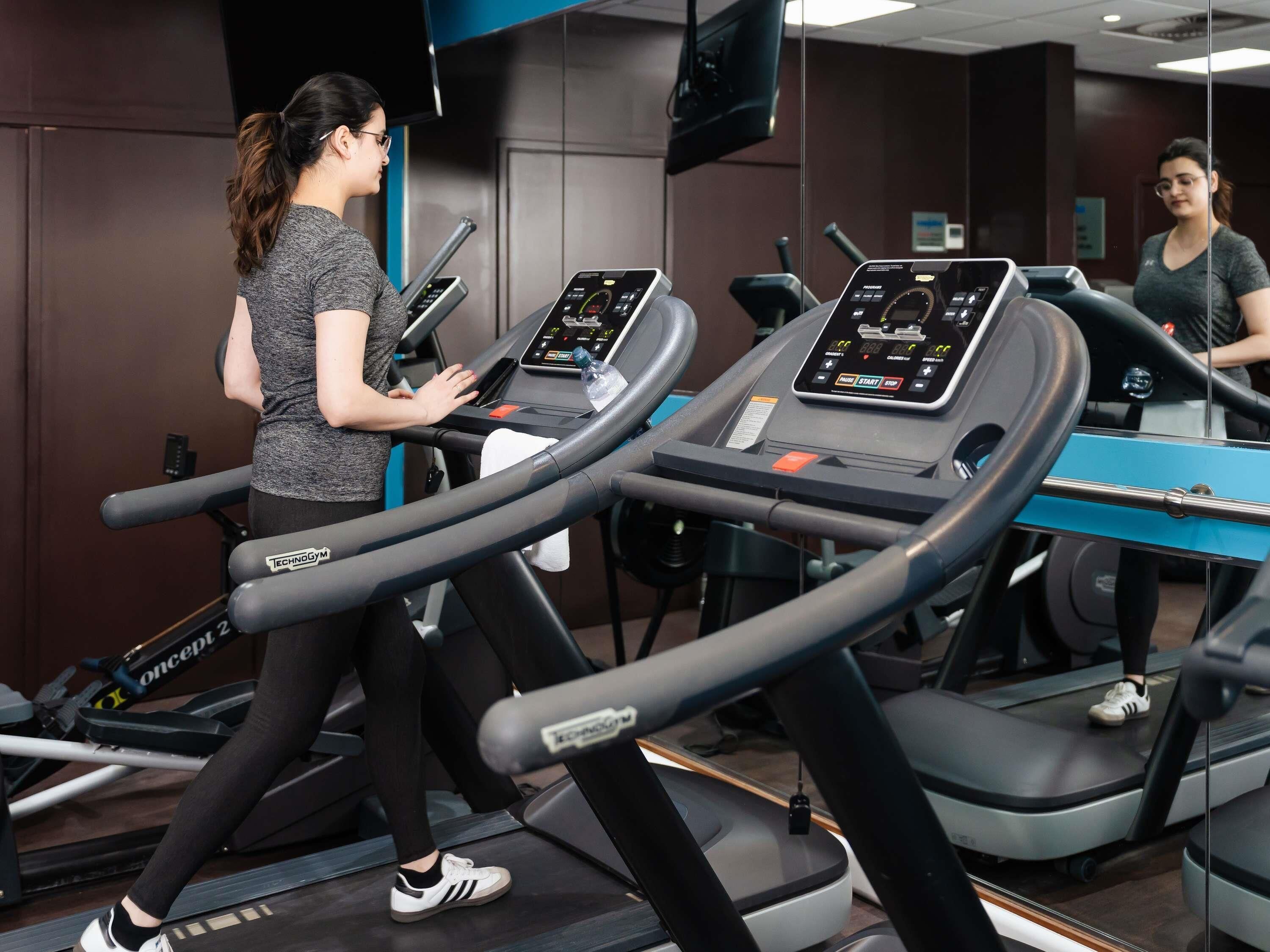 A gym with treadmills, a mirror, and a TV screen.