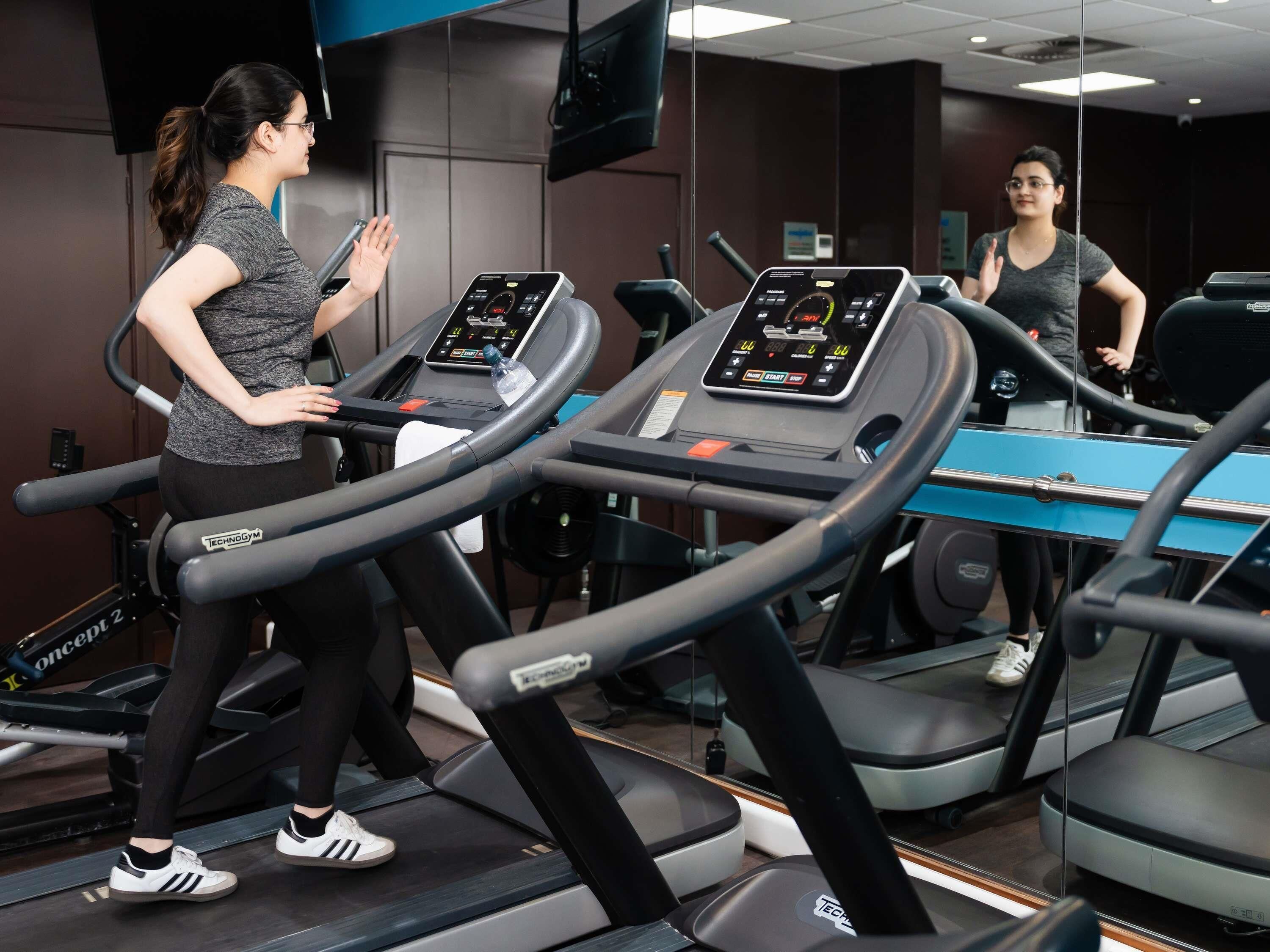 A gym with treadmills, mirrors, and a digital display on each machine.