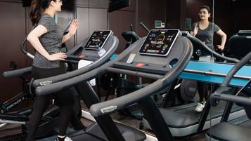 A gym with treadmills, mirrors, and a digital display on each machine.