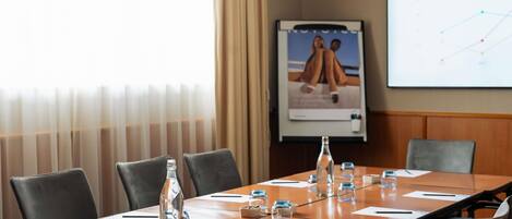 Une salle de conférence avec une longue table, des chaises, des bouteilles d’eau, des verres et un écran de présentation affichant un graphique illustrant les tendances du marché.