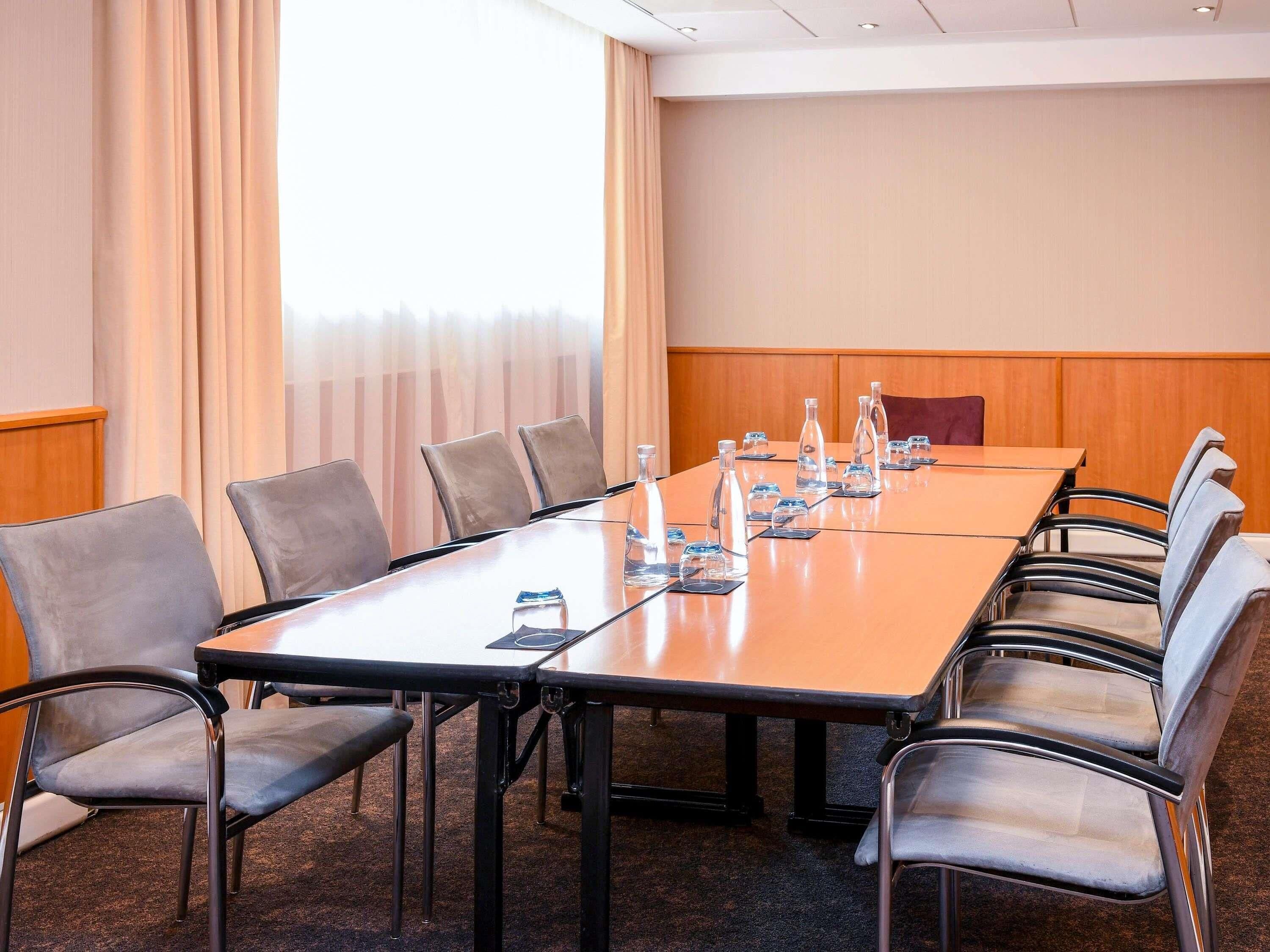 A conference room with a long table, chairs, water bottles, and glasses.