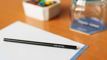 Un escritorio con un lápiz negro, un recipiente pequeño con objetos de colores y un frasco de vidrio transparente con etiqueta azul.