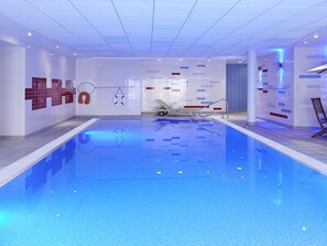 A swimming pool with tiled walls, a lifebuoy, and a lounge chair. - Novotel Milton Keynes (Milton Keynes)