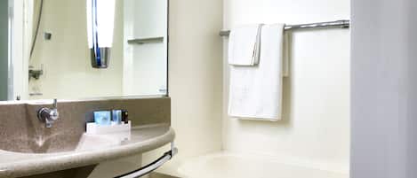 Un baño moderno con lavamanos, espejo y bañera.
