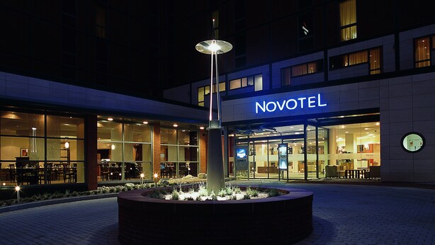A Novotel hotel with a well-lit outdoor area featuring a circular planter with plants and a tall, illuminated light fixture. - Novotel Leeds Centre (Leeds)