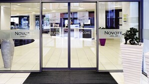 The entrance of Novotel Leeds Centre with glass doors, a reception desk, and a large vase. - Novotel Leeds Centre (Leeds)