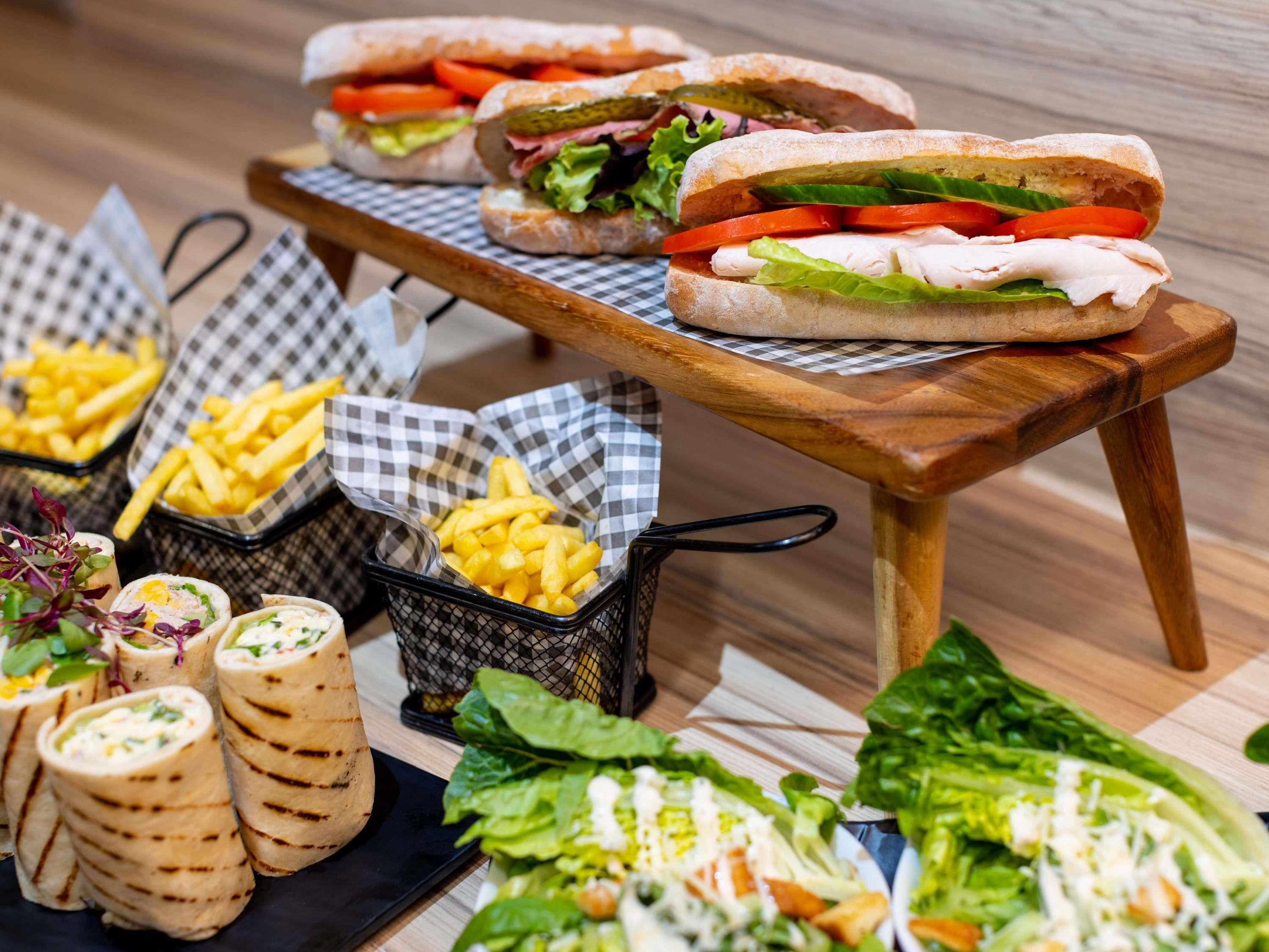 A food display with sandwiches, fries, wraps, and salads.