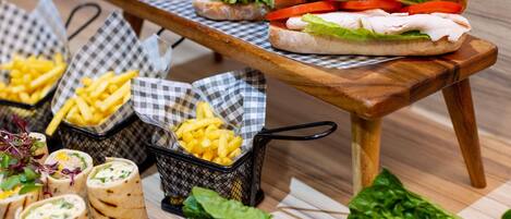 A food display with sandwiches, fries, wraps, and salads.