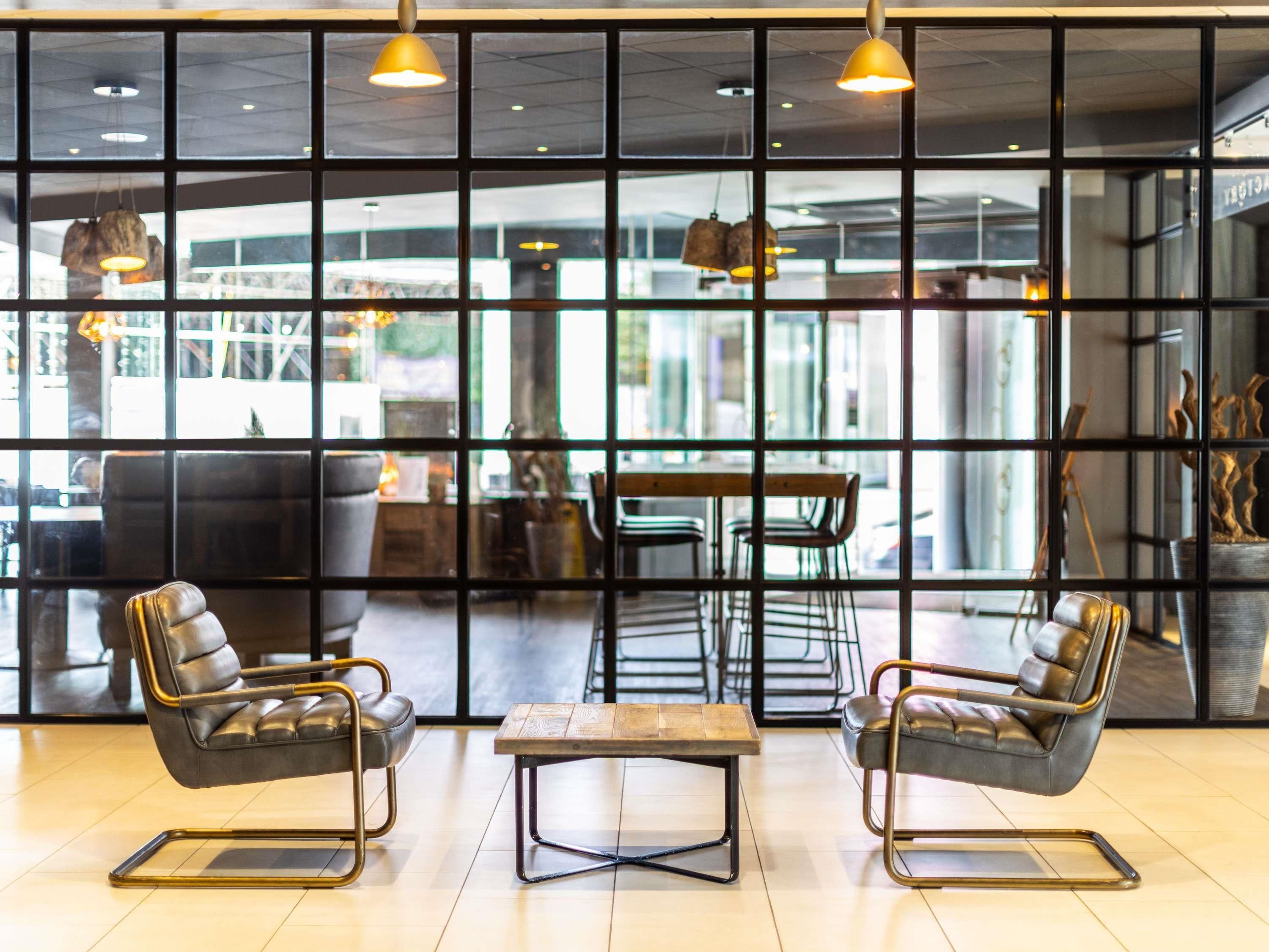 A modern interior with leather chairs, a wooden table, and pendant lighting.
