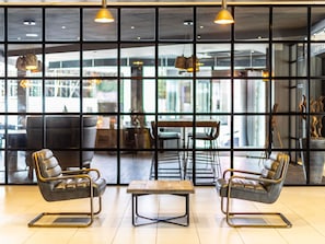 A modern interior with leather chairs, a wooden table, and pendant lighting. - Novotel Leeds Centre (Leeds)