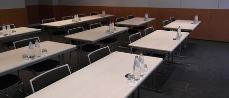 A conference room with multiple tables, chairs, and water bottles.