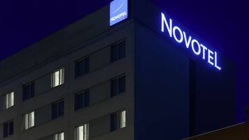 Et oplyst Novotel hotelbygning om natten med skilte.