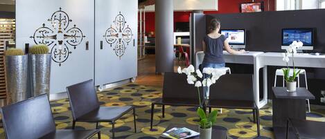 A modern hotel lobby with a reception desk, seating area, and decorative wall panels.