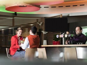 A modern bar area with a counter, multiple taps, and a seating arrangement. - Novotel Leuven Centrum (Leuven)