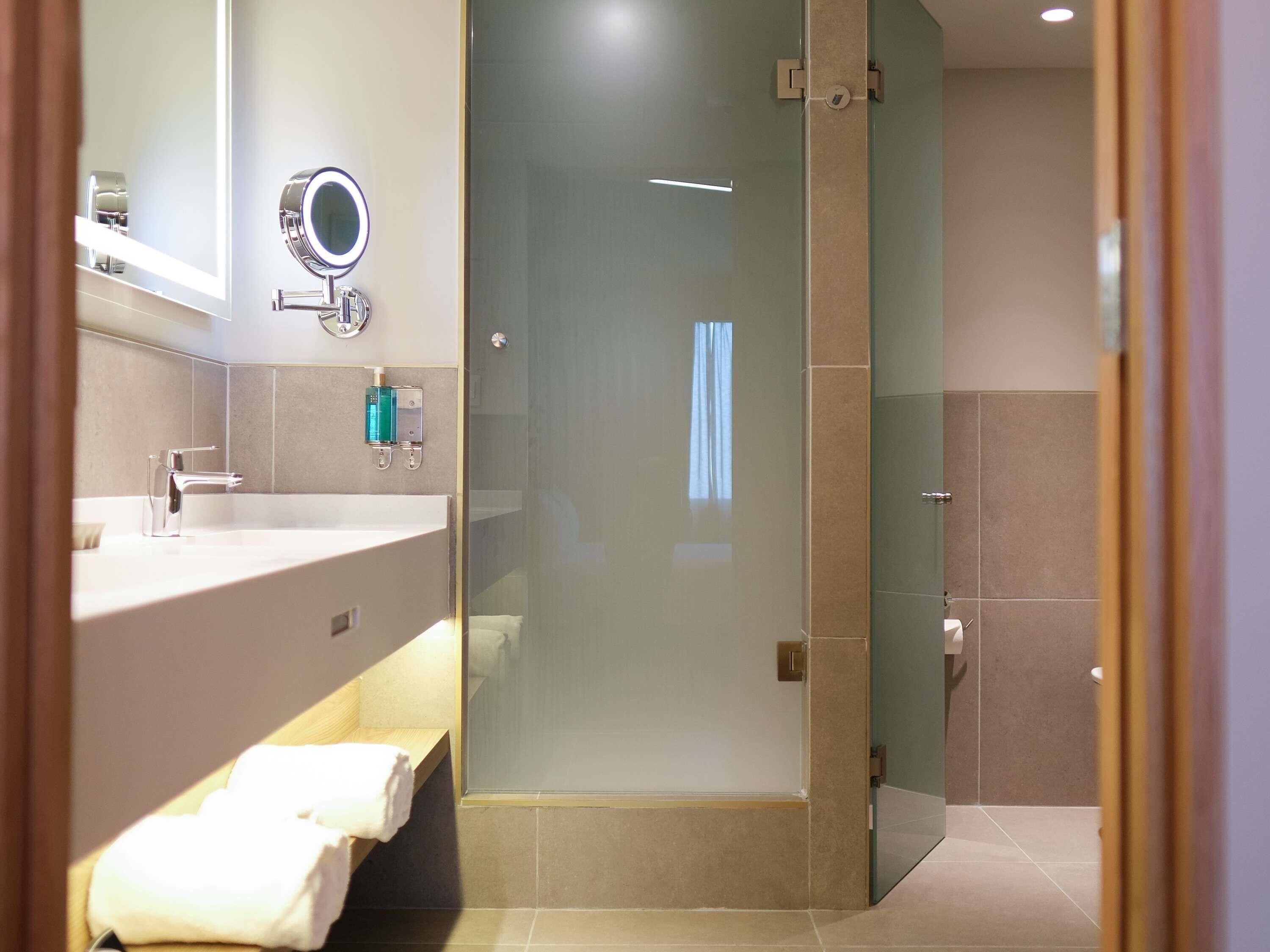 Un bagno moderno con cabina doccia in vetro, un mobile lavabo con specchio e un porta asciugamani.