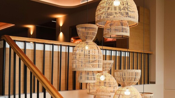 A staircase with a wooden handrail and black balusters, leading to a landing with a modern light fixture.