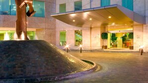 A modern hotel entrance with a central water feature and a large metal sculpture.