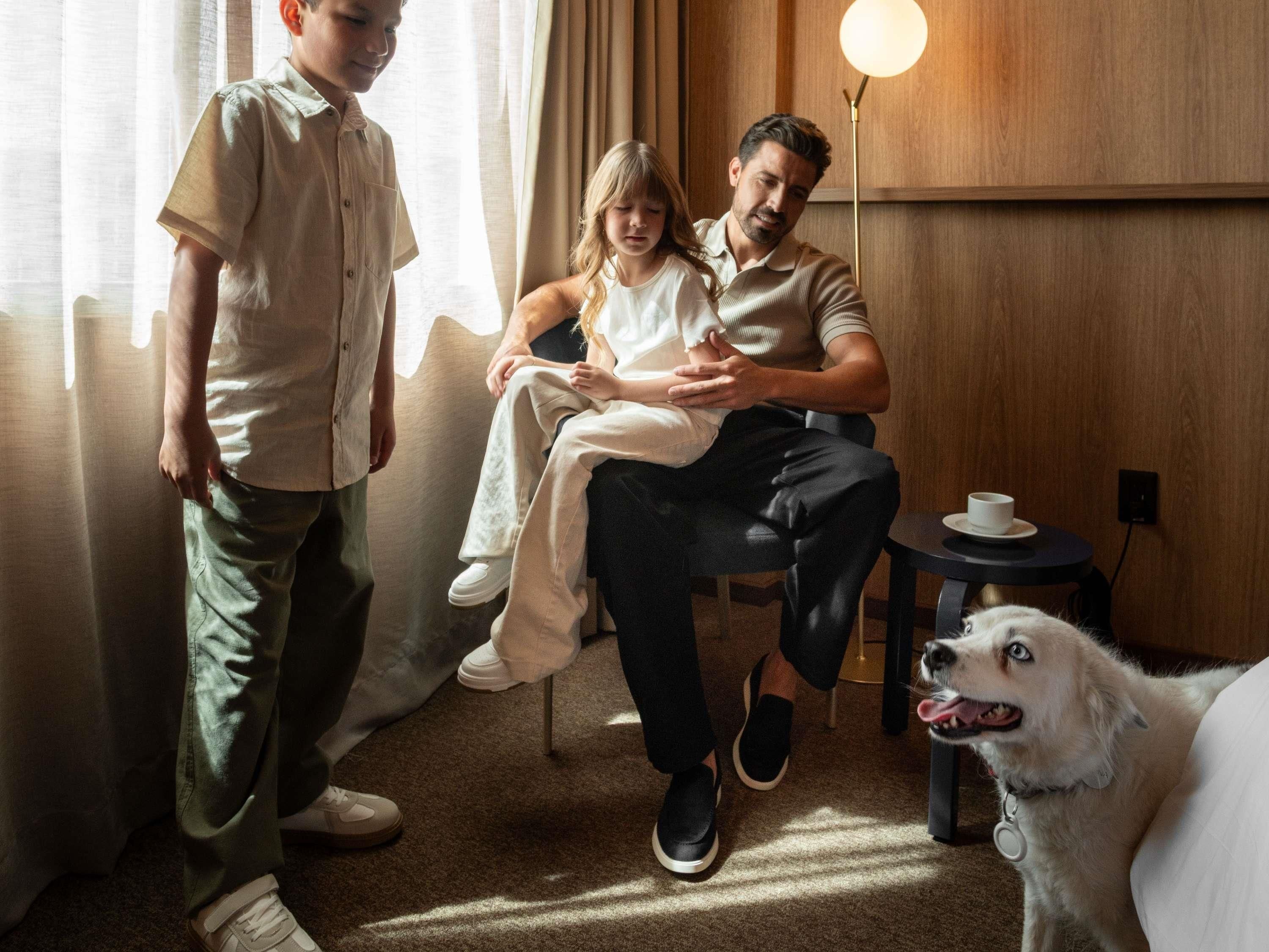 A room with a sofa, a small round table with a cup, a standing lamp, and a dog.