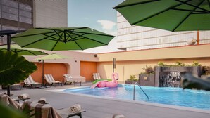 A pool area with lounge chairs, umbrellas, and a decorative flamingo float.