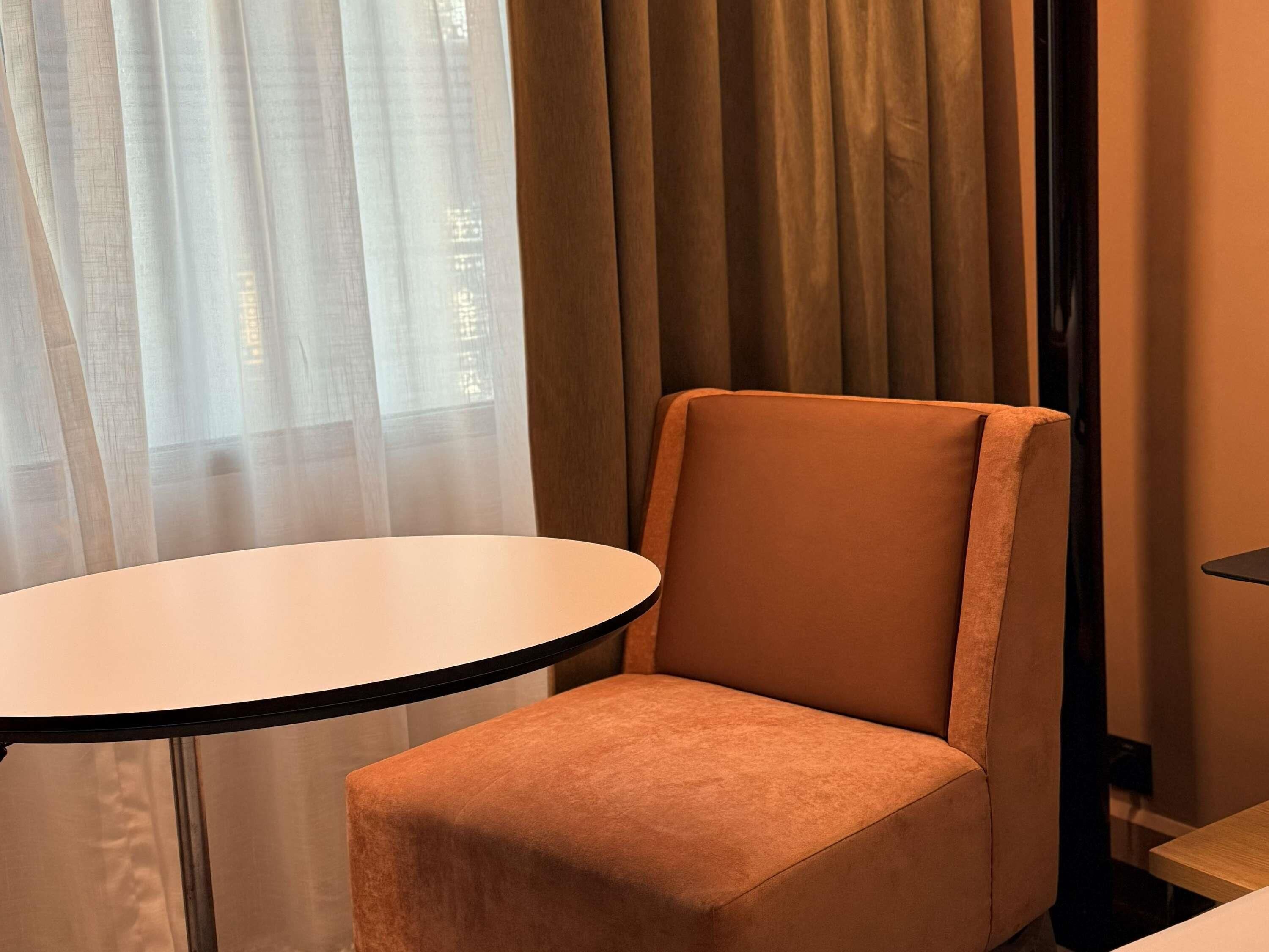 Una habitación con una mesa redonda y una silla acolchada.