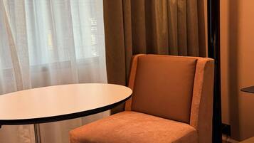 Una habitación con una mesa redonda y una silla acolchada.
