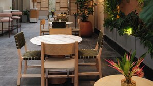 A modern indoor dining area with wooden furniture, a round table, and potted plants.