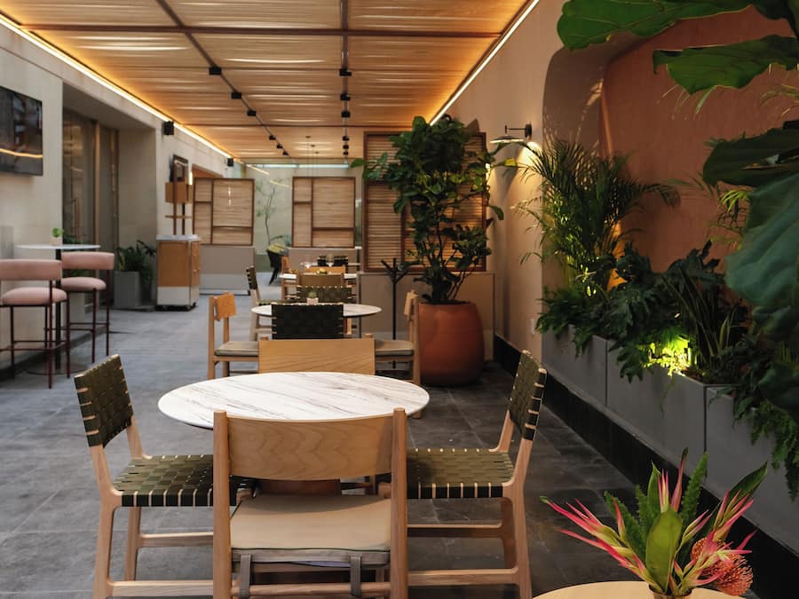 Un comedor moderno con mobiliario de madera, una mesa redonda y plantas en macetas.